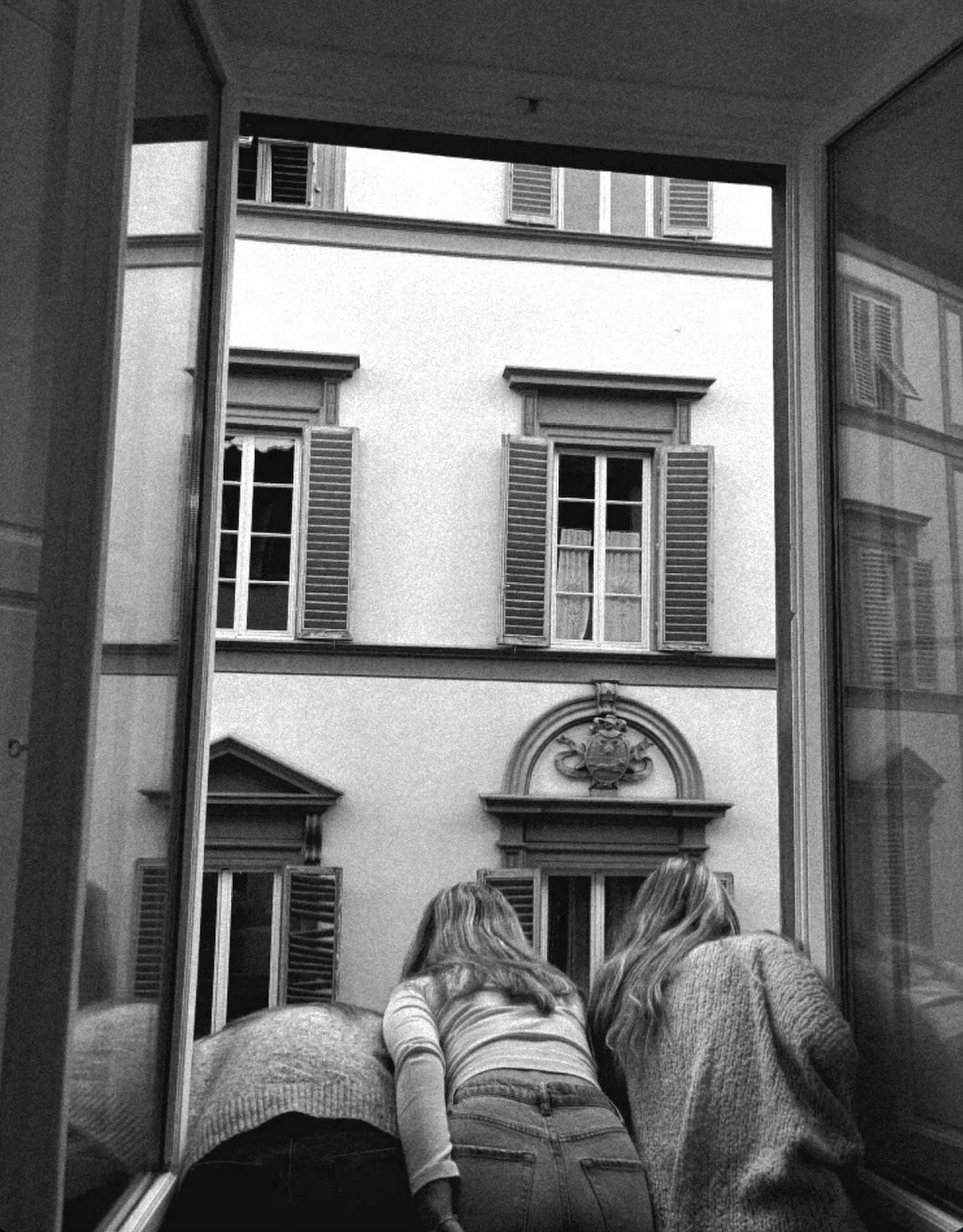 College Students in Italy enjoying their time together and hanging out of a window in their home city.